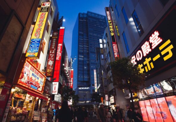 Street view of Tokyo's bustling nightlife with illuminated storefronts and skyscrapers.